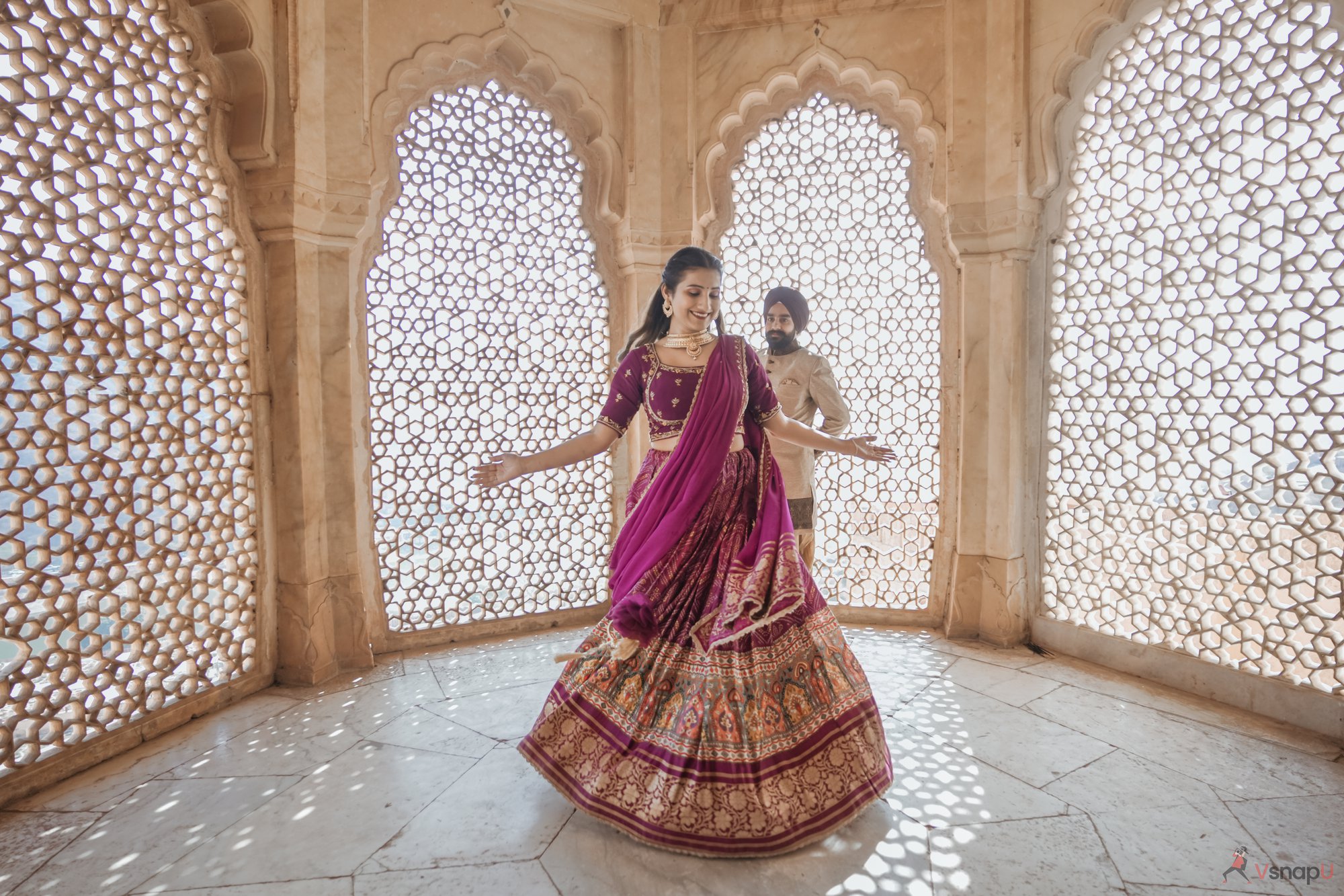 Ethnic Punjabi couple dancing in a fort, surrounded by sunlight streaming in from the stone walls, perfect for a romantic pre-wedding shoot.